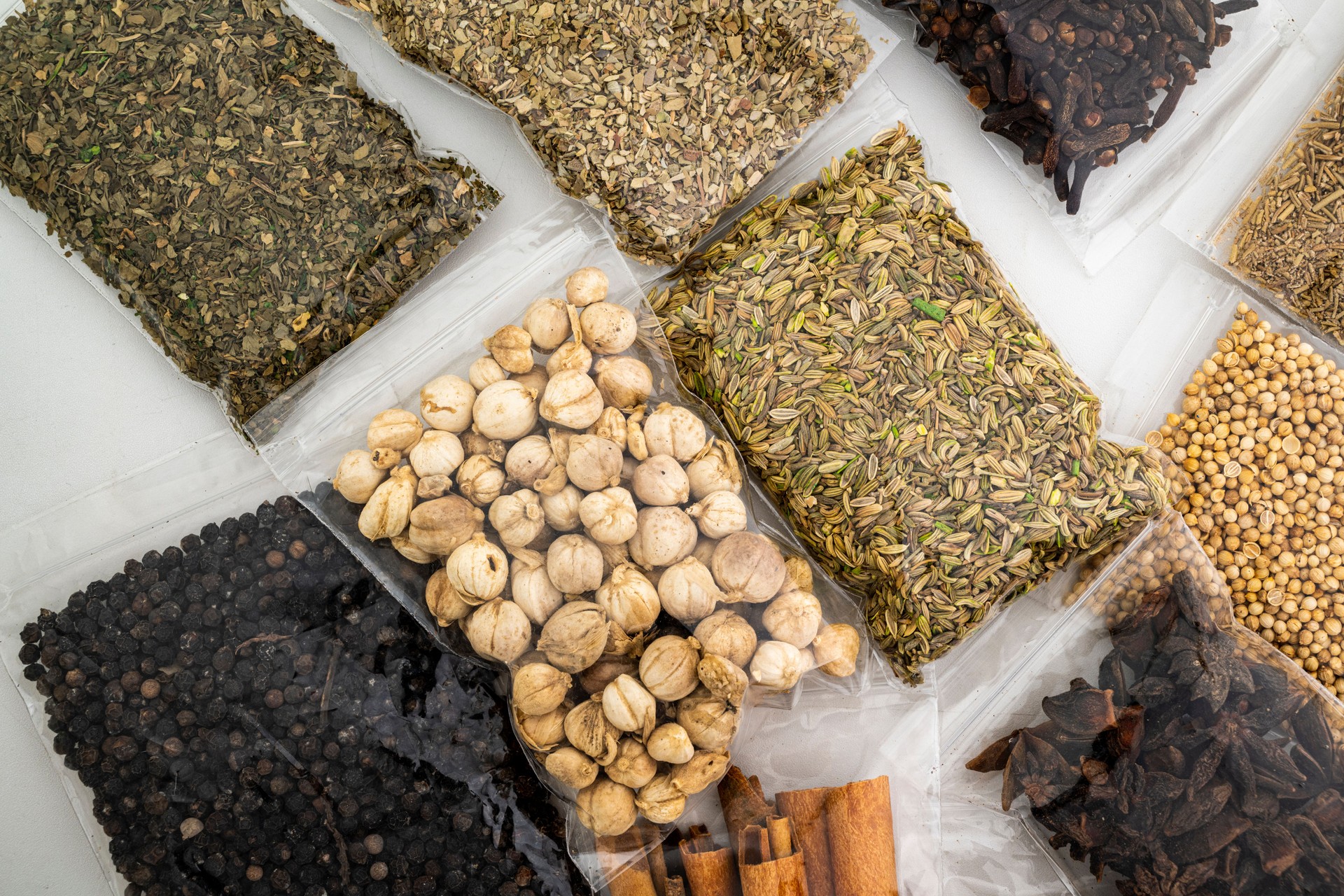 A variety of spices and nuts are displayed in plastic bags